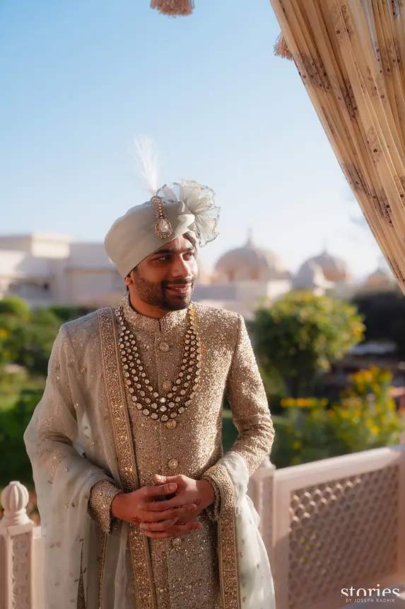 Groom in ivory sherwani with feathered kalgi and layered pearl mala