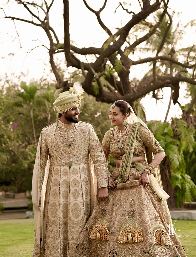 Groom and bride in gold outfits, garden portrait