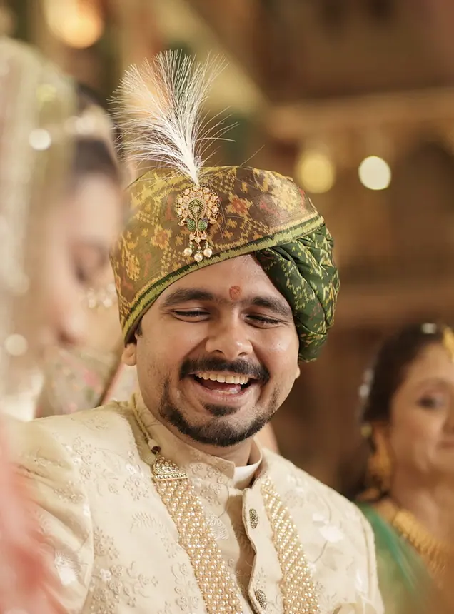 Smiling groom in green and gold safa with feather kalgi