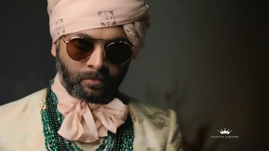 Close-up of a groom in blush turban with sunglasses and emerald mala