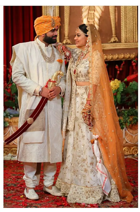Groom in orange safa with the bride and a sword