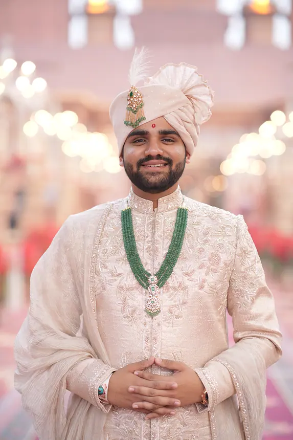 Smiling groom in blush safa with emerald mala